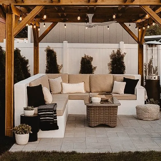 Outdoor seating area under a wooden pergola built with screw piles, featuring cozy cushions and string lights.
